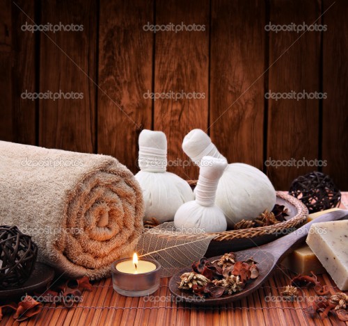 Spa massage setting with thai herbal compress stamps and candlelight
