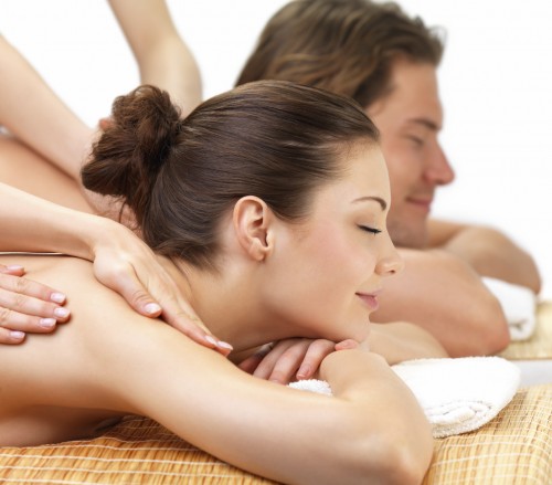 Young beautiful happy woman getting a massage at the spa with her boyfriend